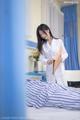 A woman in a white lab coat standing next to a bed.