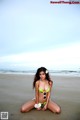 A woman in a bikini sitting on the beach.