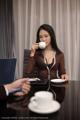 A woman sitting at a table with a cup of coffee.