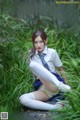 A woman in a school uniform is sitting in the grass.