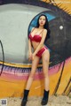 A woman in a red bikini posing in front of a graffiti wall.