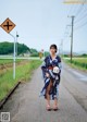 A woman in a blue and white kimono walking down a road.