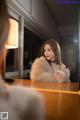 A woman sitting at a table in front of a mirror.