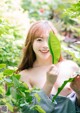 A young woman holding a green leaf in her hand.