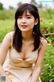 A woman in a beige dress sitting in a field of flowers.