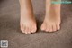 A close up of a person's bare feet on a carpet.