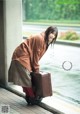 A woman leaning against a wall with a suitcase.