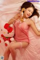 A woman in a pink lingerie laying on a bed with a hello kitty.