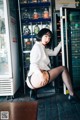 A woman in a white shirt and black stockings posing in front of a refrigerator.