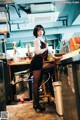 A woman sitting on a stool in a kitchen.