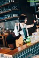 A woman is pouring a drink at a bar.