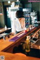 A woman standing behind a bar in a restaurant.