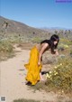 A woman in a yellow dress standing in a field of flowers.