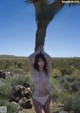 A woman in a white lingerie standing next to a palm tree.