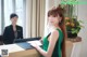 A woman in a green dress standing at a reception desk.