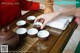 A woman is preparing tea on a wooden tray.