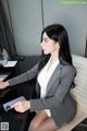 A woman sitting at a desk using a cell phone.