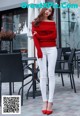 A woman in a red sweater and white pants posing for a picture.