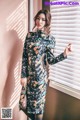 A woman standing in front of a window wearing a black floral dress.