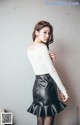 A woman in a white top and black leather skirt.