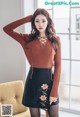 a woman in a brown sweater and black skirt posing for a picture