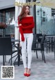 A woman wearing white jeans and a red sweater.