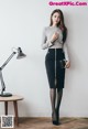 A woman standing next to a table with a lamp on it.