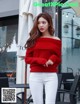 A woman wearing a red sweater and white pants.