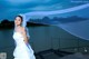 A woman in a wedding dress standing on a dock.