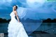 A woman in a wedding dress standing on a dock.