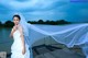 A woman in a wedding dress standing on a dock.