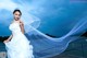 A woman in a wedding dress standing on a dock.