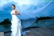 A woman in a wedding dress standing on a dock.