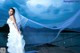 A woman in a wedding dress standing on a dock.