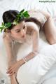 A woman laying on a bed with a flower crown on her head.